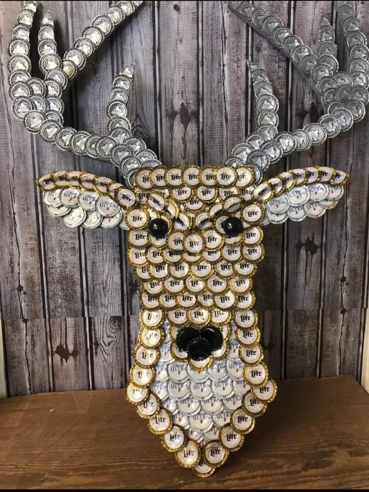 a deer head made out of bottle caps on a wooden wall with beads and chains around it