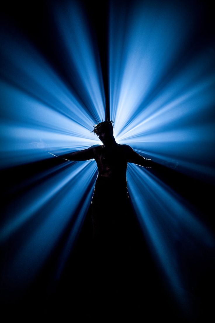 a person standing in the middle of a room with blue light coming from behind them