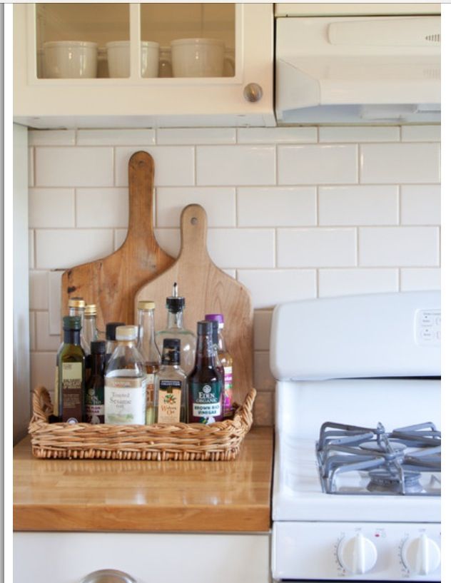 a wooden cutting board sitting on top of a kitchen counter next to bottles and knives