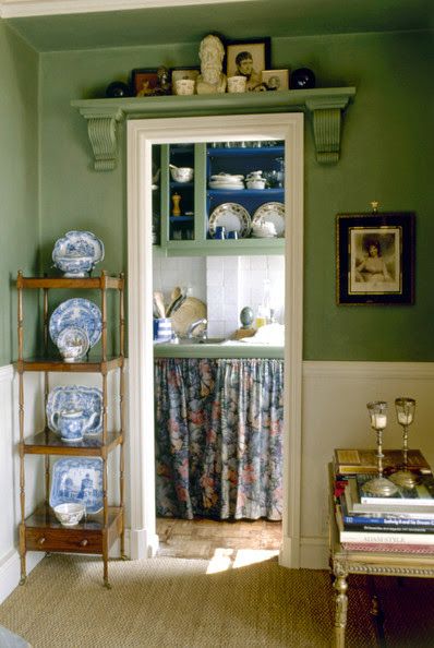 a room with green walls and blue plates on the shelf in front of the door