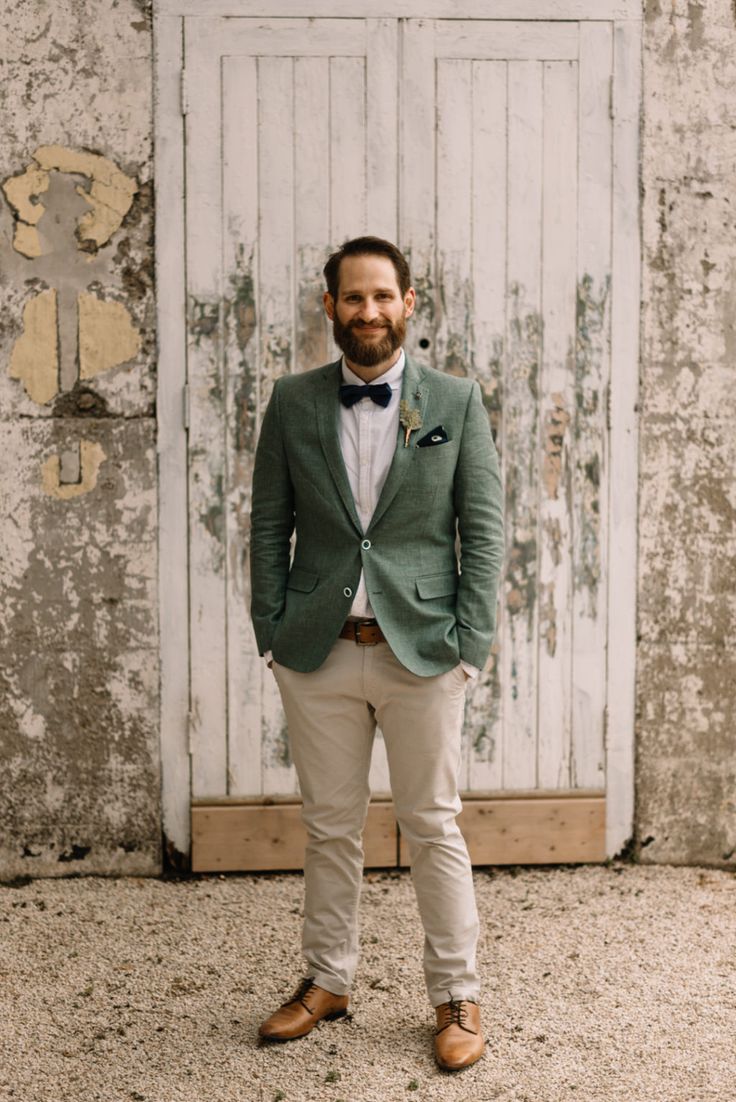 a man standing in front of a white door wearing a green jacket and bow tie