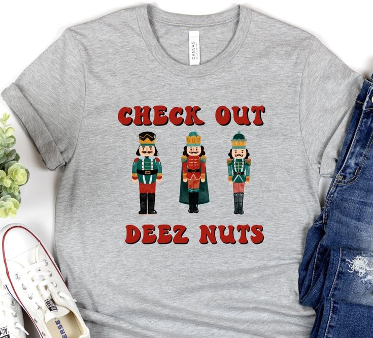 "Looking for a funny Christmas shirt that will make you the life of the party? Look no further than Deez Nuts! This hilarious t-shirt features colorful nutcrackers standing in a line with festive red and green outfits. Plus, the slogan \"check out deez nuts\" is sure to get a laugh from anyone who sees it. So put on your jolly best and order Deez Nuts funny Christmas shirt today! Soft cotton and quality print make users fall in love with it over and over again. These t-shirts have-ribbed knit co Funny Christmas Shirts Zazzle, Funny Xmas Tshirts, Christmas Tees Funny, Funny Christmas Shirts Hilarious, Christmas Shirt Ideas Funny, Friend Christmas Party, Funny Family Christmas Shirts, Funny Christmas Pajamas, Funny Christmas T Shirts