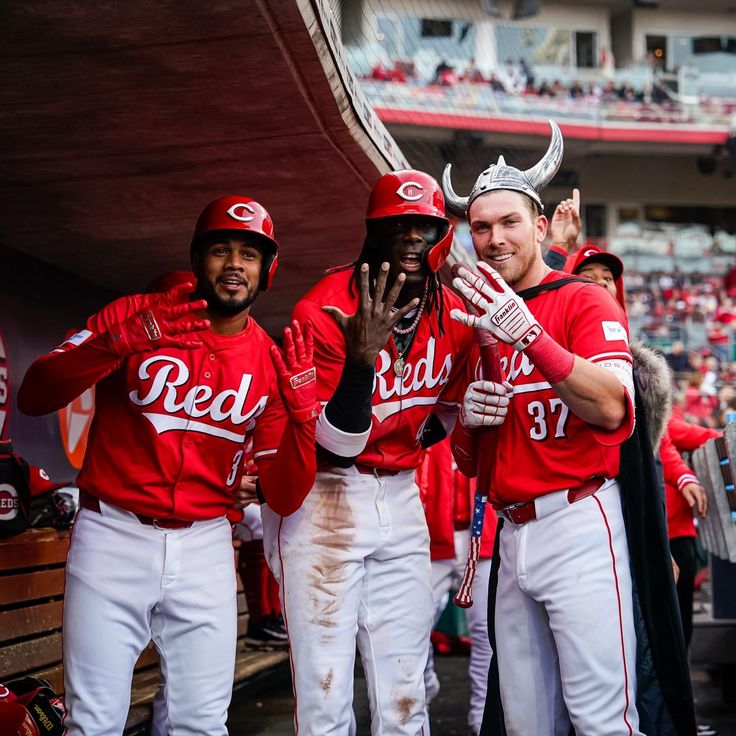 three baseball players in red and white uniforms are standing together with their hands up to the camera