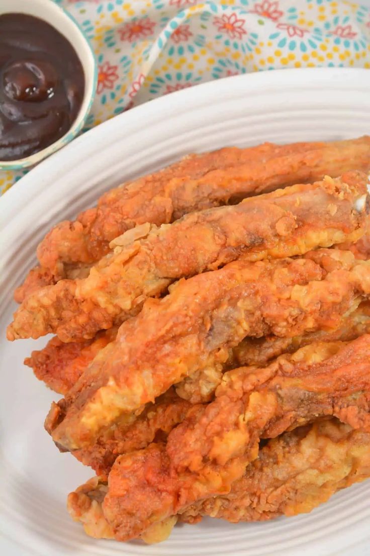 some fried food on a white plate next to dipping sauce and a cup of ketchup