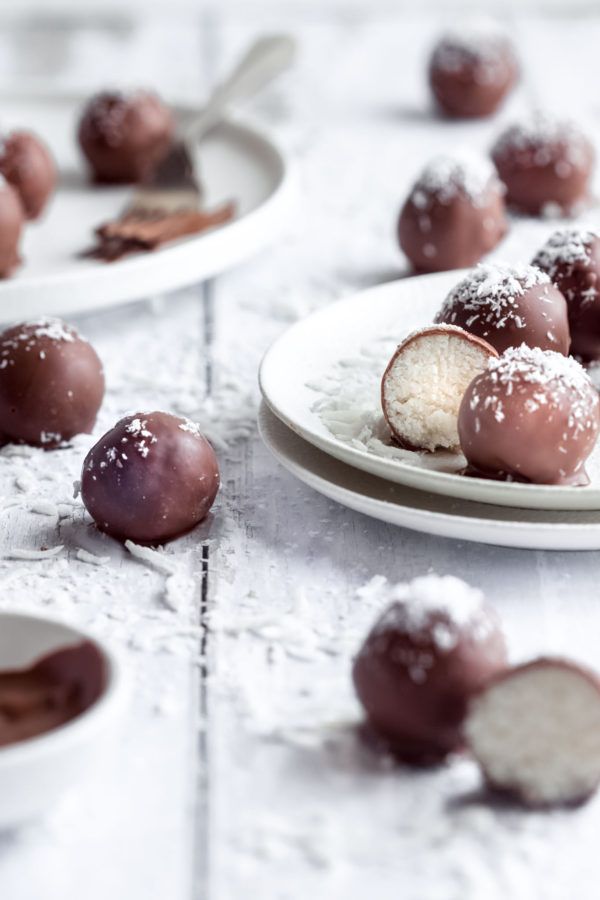 two plates filled with chocolate covered desserts on top of a white table next to another plate