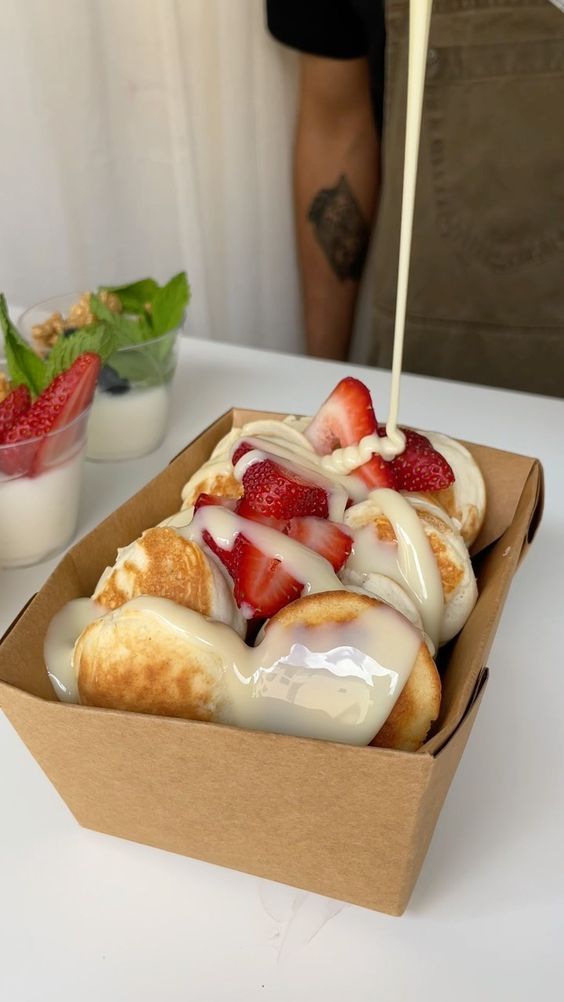 a box filled with pastry covered in icing and strawberries