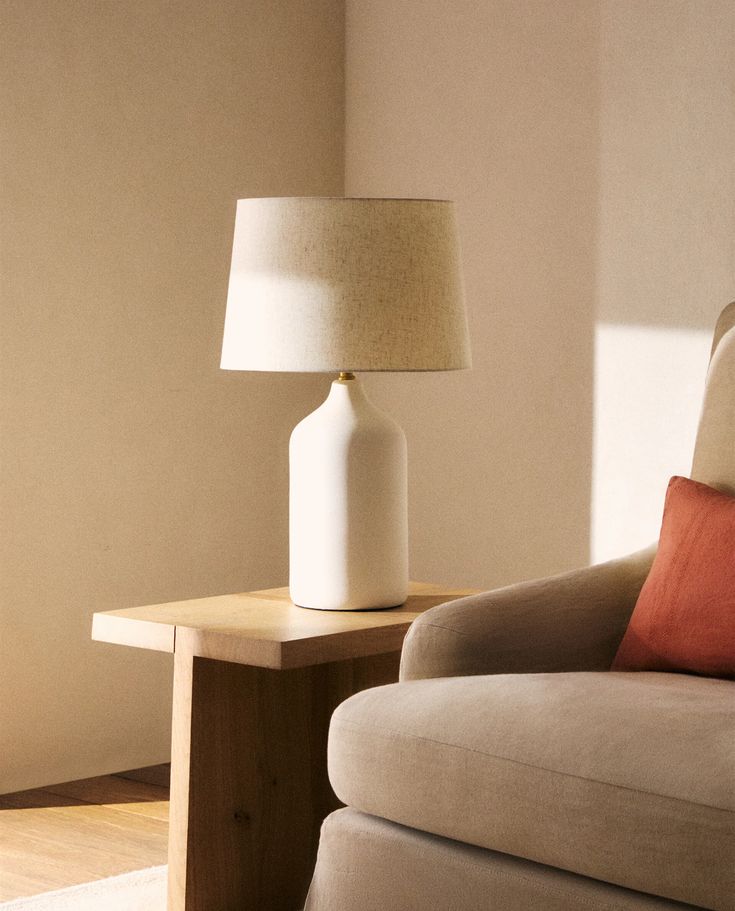 a white lamp sitting on top of a table next to a chair in a living room