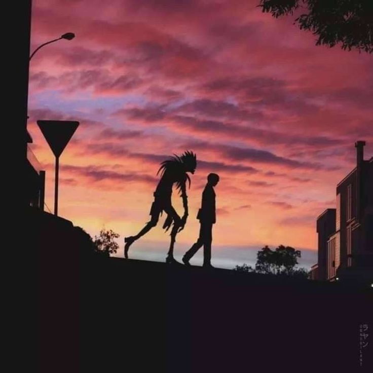 two people are walking down the hill at sunset