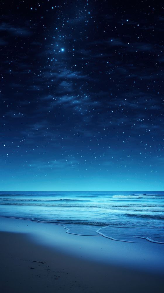 the night sky is lit up by stars above the ocean and sand on the beach