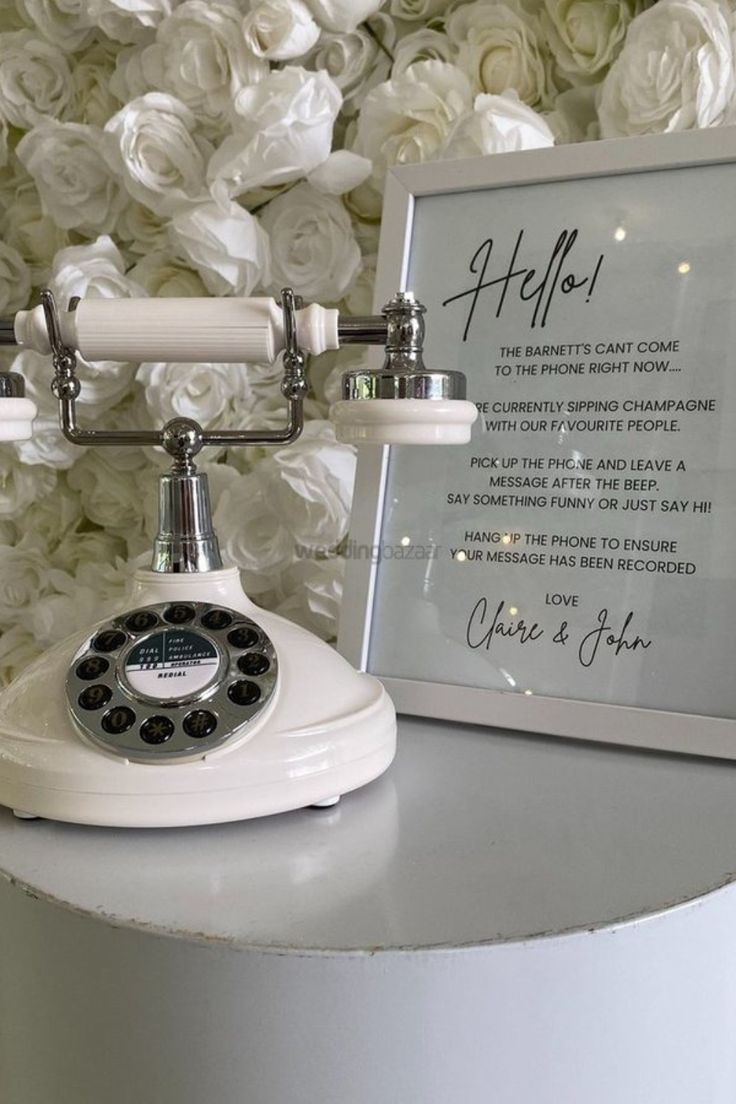 an old fashioned phone sitting on top of a table next to a white flower wall