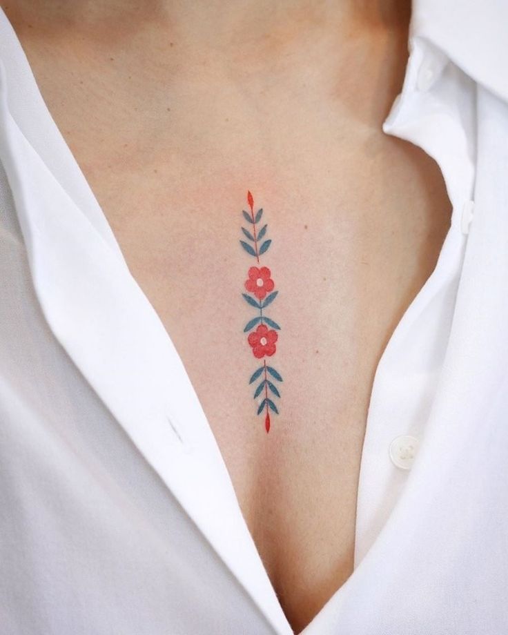 a woman's chest with red flowers and leaves painted on her chest, while she is wearing a white shirt