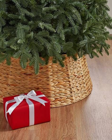 a christmas tree in a basket next to a present