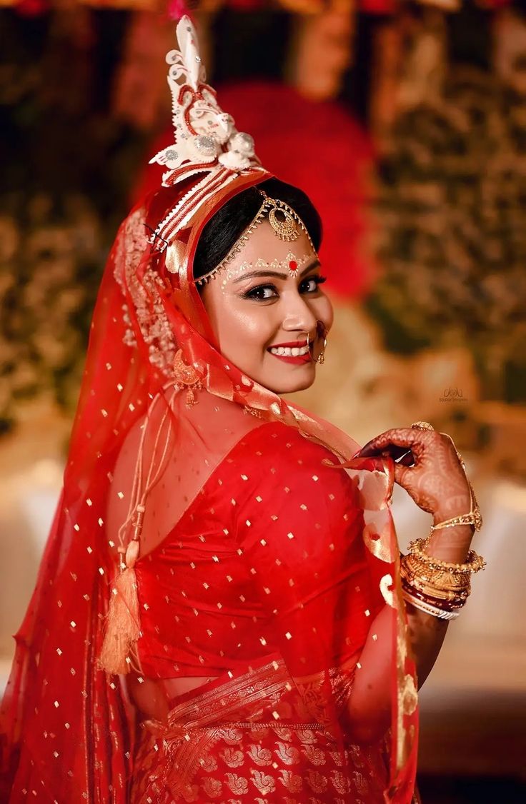 a woman dressed in red and gold poses for the camera