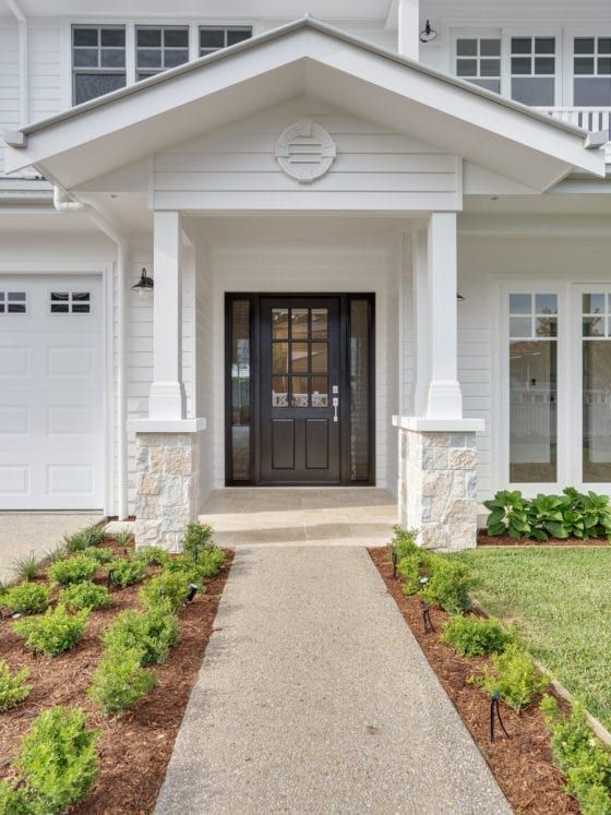 a white house with black front door and two car garages on the side walk