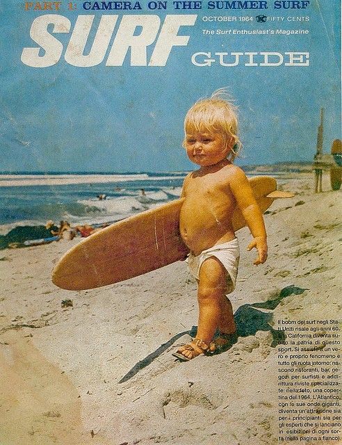 a young child holding a surfboard on top of a sandy beach