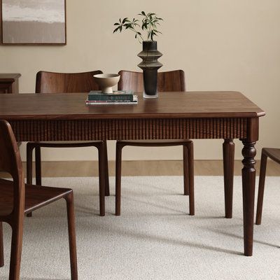 a wooden table with chairs around it and a vase on the table next to it