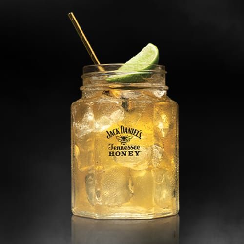 a mason jar filled with ice and a lime slice on the rim next to a straw