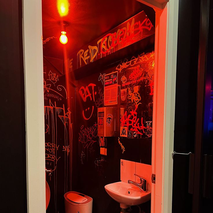 a bathroom with graffiti on the walls and a sink in the corner next to it