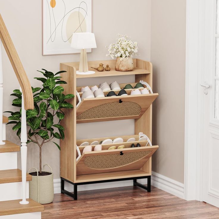 a wooden shelf filled with lots of shoes next to a potted plant on top of a hard wood floor