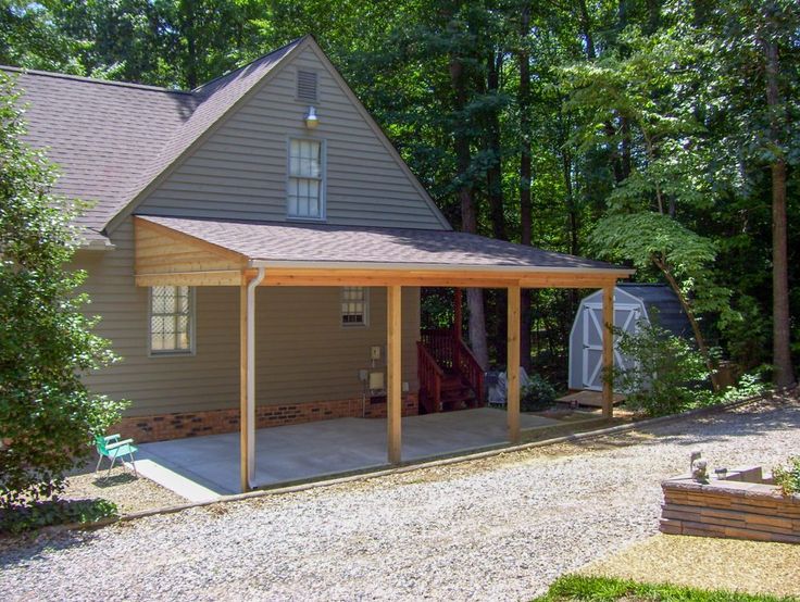 a house with a carport in front of it and lots of trees around it