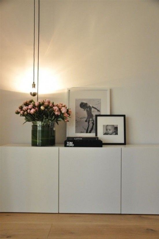 a vase filled with flowers sitting on top of a white shelf next to a lamp