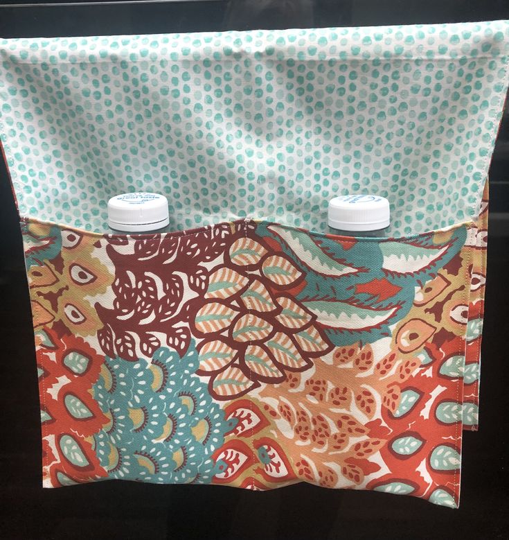 two cups are sitting in front of a colorful fabric bag with polka dots on it