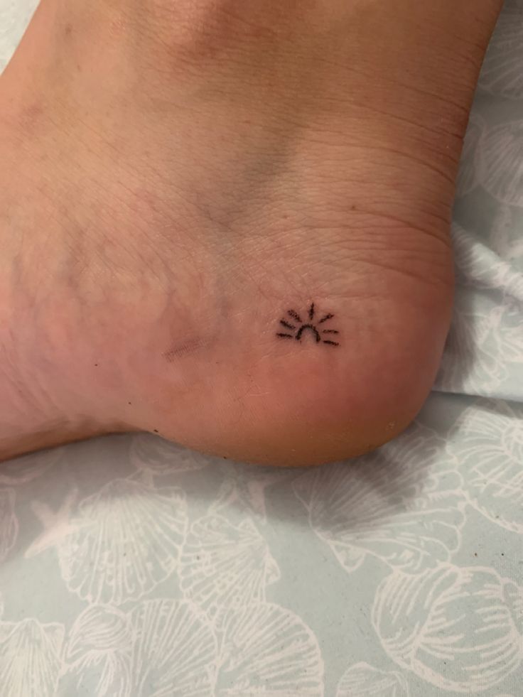 a person with a small sun tattoo on their foot