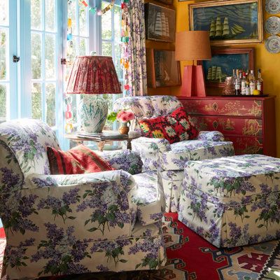 a living room filled with lots of furniture and flowers on the walls, along with a red rug