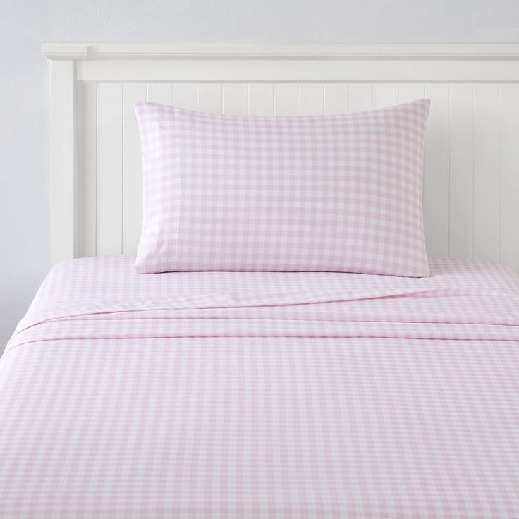 a pink and white checkered bed spread with pillows