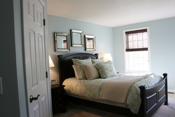 a bed sitting in a bedroom next to a window with two framed pictures on the wall