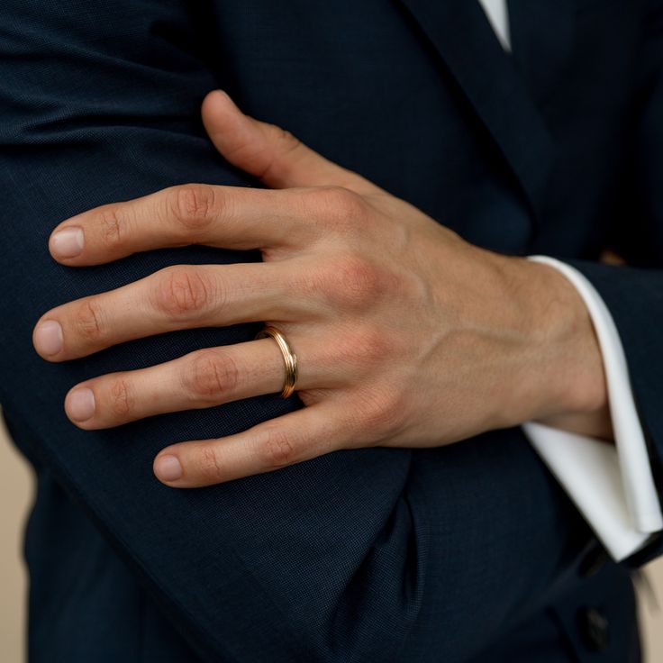 a man in a suit with his hands on his chest wearing a gold wedding ring