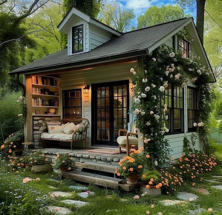 a small house with flowers on the porch