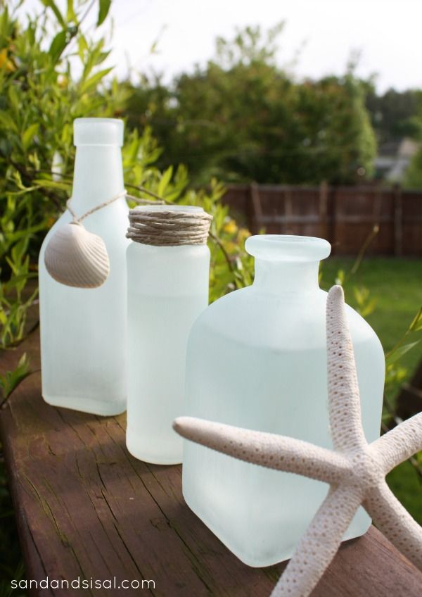 three white glass bottles sitting on top of a wooden table next to a starfish