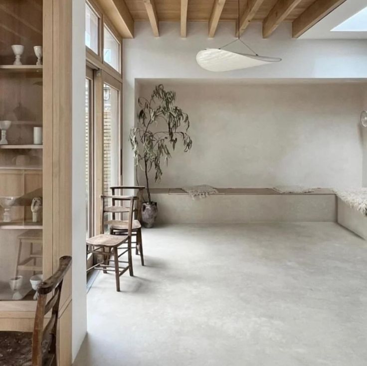 an empty room with white walls and wooden ceilinging, along with chairs and tables