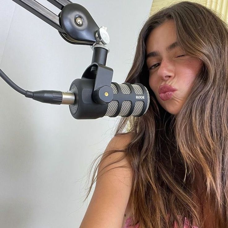 a woman with long hair holding a microphone up to her face and looking at the camera