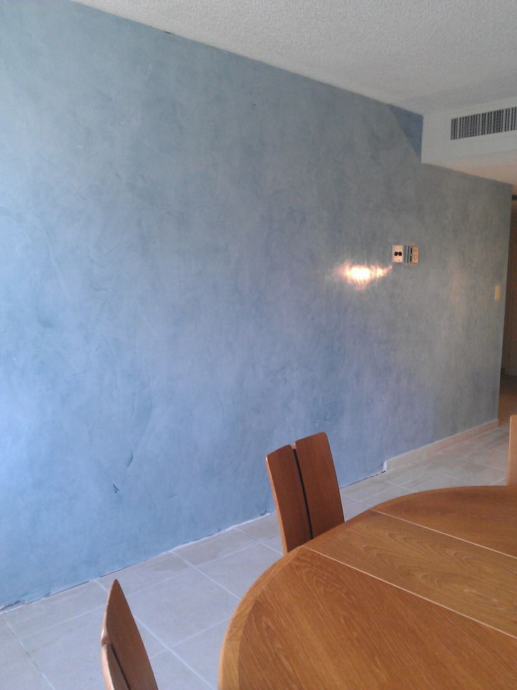 an empty room with blue walls and wooden furniture in it, as well as a round dining table