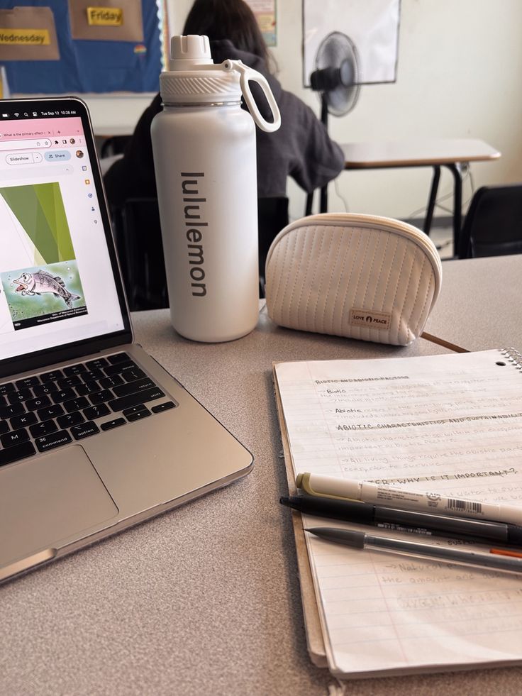 an open laptop computer sitting on top of a table next to a notebook and pen