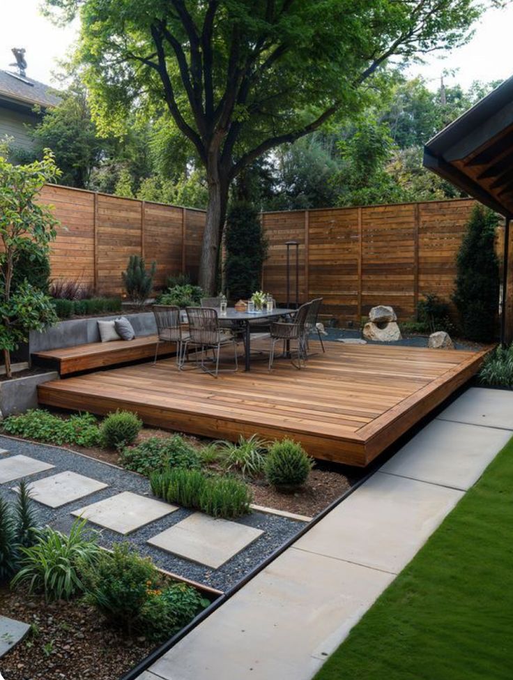 a wooden deck in the middle of a garden with seating area and trees around it