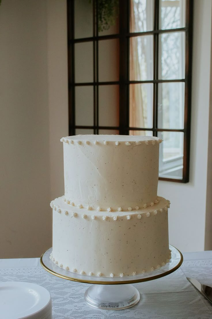 a three tiered cake sitting on top of a table next to a plate and window