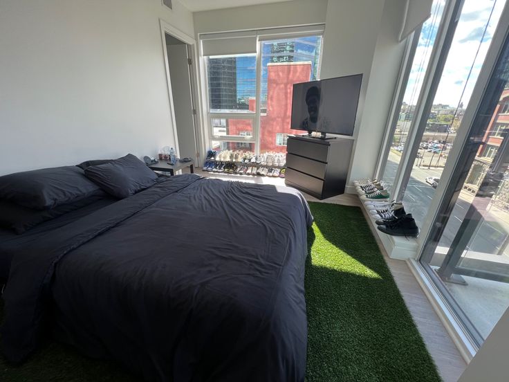 a bedroom with a large bed and green carpeted area in front of the window