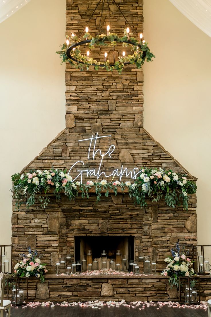 the fireplace is decorated with greenery and candles for an elegant wedding reception at stoneridge country club