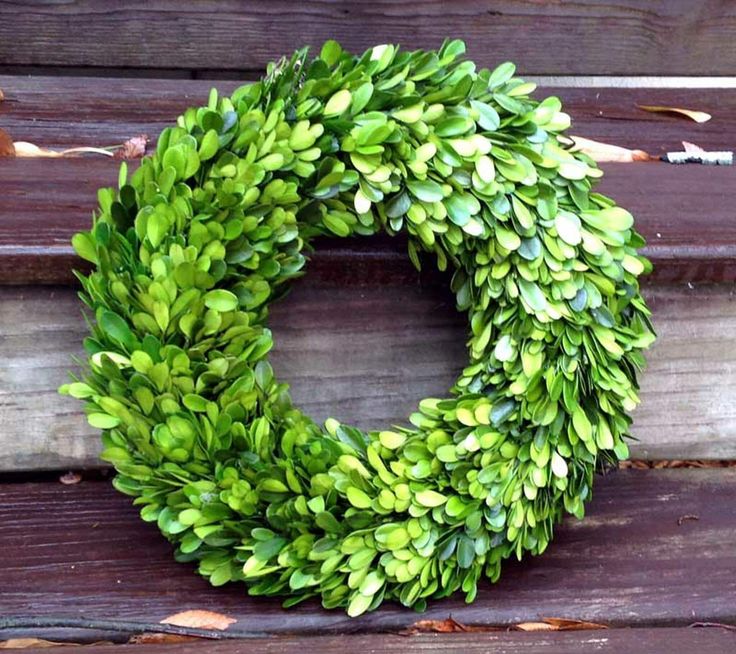 a green wreath sitting on top of a wooden bench