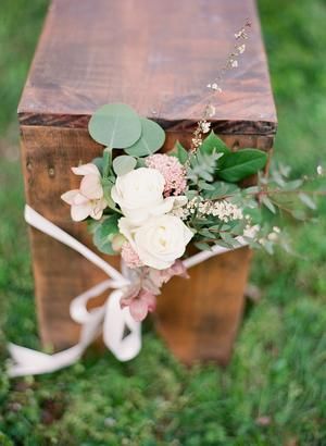 a wooden box with flowers and greenery tied to the top is sitting on some grass