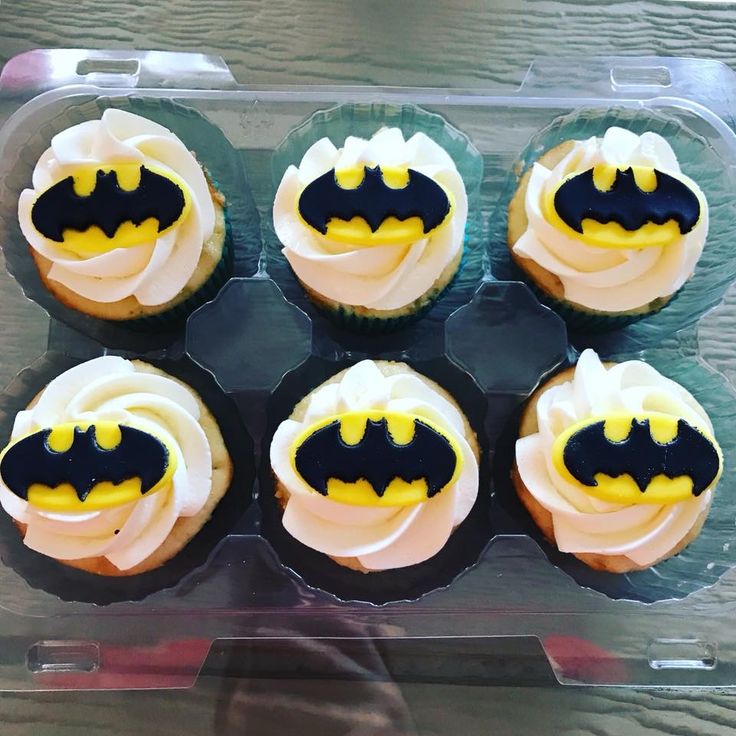 six cupcakes with white frosting and yellow icing decorated like batman's