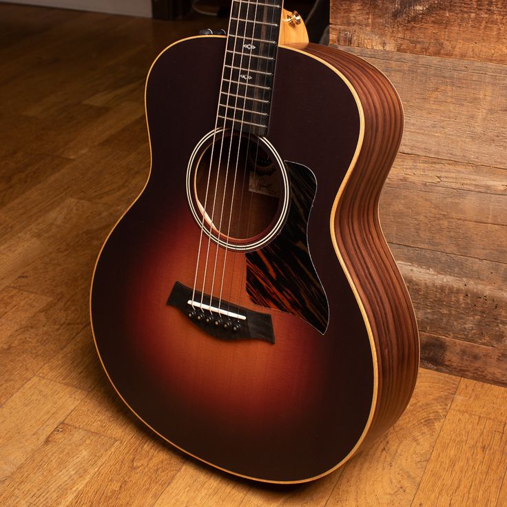 an acoustic guitar sitting on top of a wooden floor