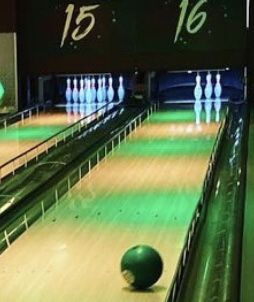 the bowling alley is full of green bowling balls and white pins with numbers on them