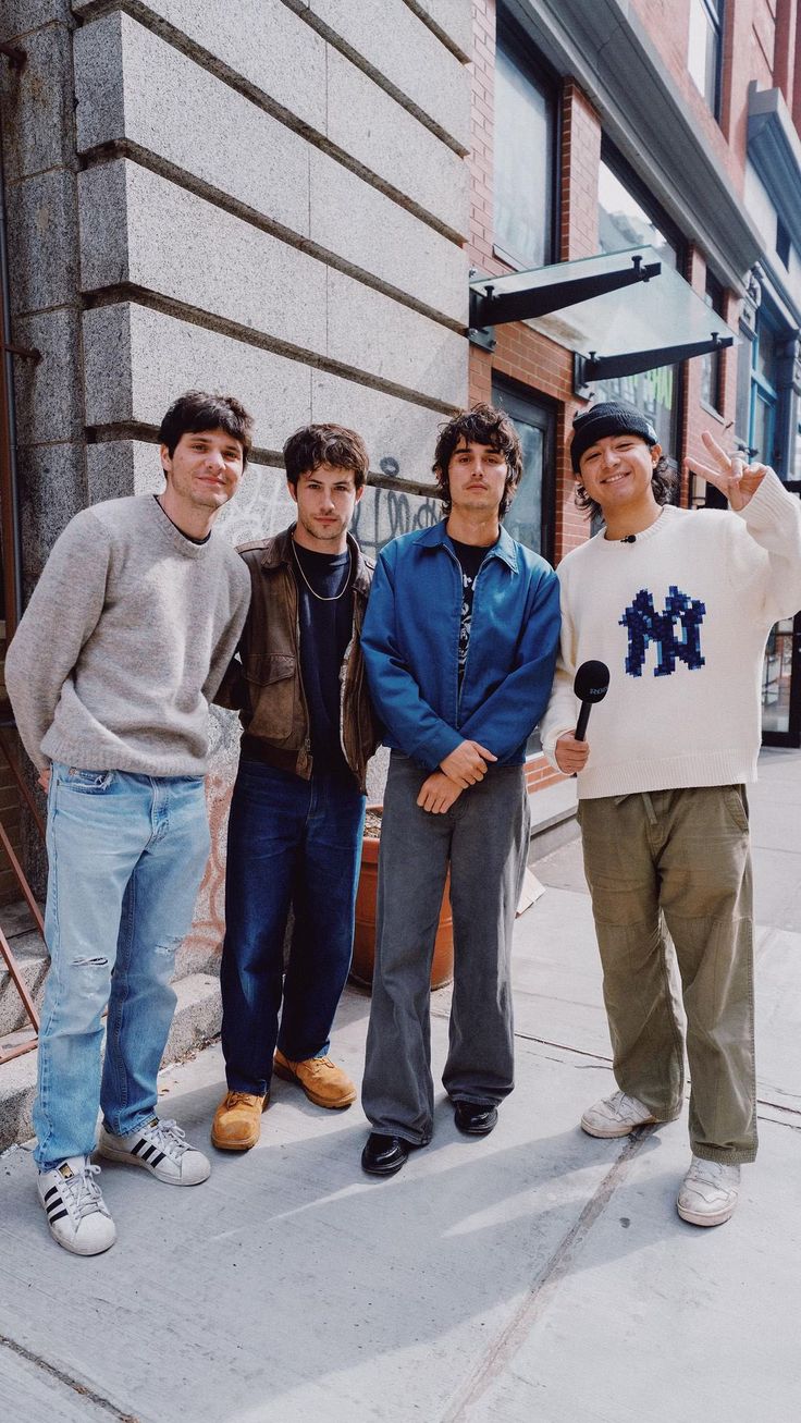 four young men standing on the sidewalk in front of a building