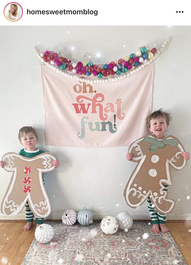 two children standing in front of a banner with gingerbreads on it