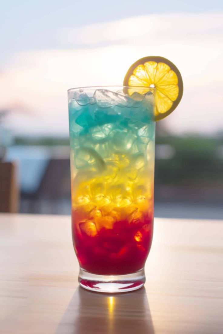 a colorful drink sitting on top of a table next to a slice of lemon wedge