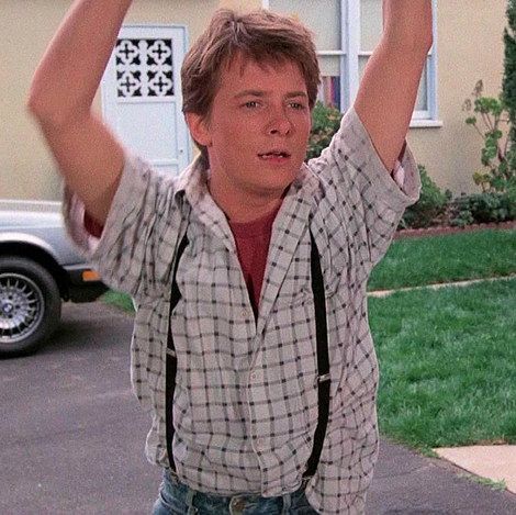 a young man is holding his hands up in the air while standing on a driveway